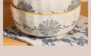 Close-up detail of ceramic bowls with blue floral underglaze design and yellow rim on fabric mat.