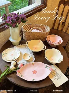 Vista dettagliata del set di stoviglie in ceramica con fiori rosa e fragole sul tavolo.