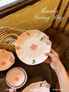 Primo piano dettagliato di un piatto di ceramica rosa con motivo a fragole e fiori su tavolo.