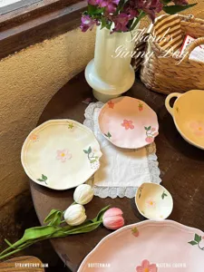 Dettaglio di stoviglie in ceramica con grazioso design in rilievo di fragole e fiori rosa.