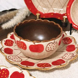 Detailed view of ceramic bowl and plate set with cute retro red apple pattern and scalloped edge.