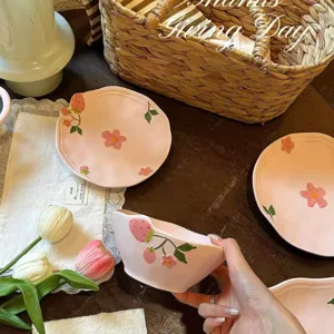Set di ciotole e piatti in ceramica rosa con motivi di fragole e fiori dipinti a mano per la tavola.