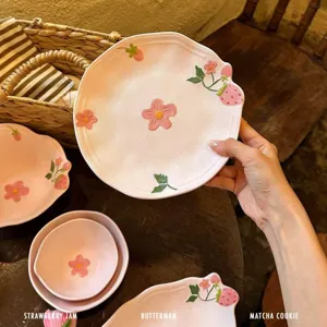 Set di stoviglie in ceramica rosa con piatti carini di fragole e fiori per la cucina.
