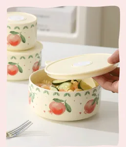 Ceramic lunch box detail showing cute fruit pattern bowl with lid open and fresh food inside.
