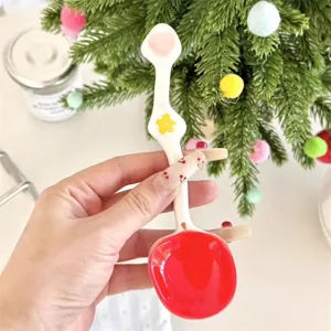 Cute ceramic spoon close-up with red bowl and floral handle detail for home tableware use.