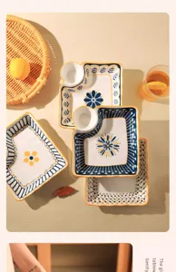 Detailed shot of ceramic partitioned dumpling plates with sauce dish and elegant blue floral design.