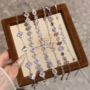 Primer plano detallado de delicadas pulseras de strass con trébol de cristal morado en expositor.
