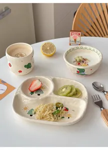 Dettaglio stoviglie ceramica con piatto diviso, ciotola e tazza dal design grazioso.