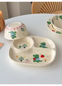 Dettaglio di stoviglie in ceramica con piatto diviso e ciotola con simpatico motivo coccodrillo.