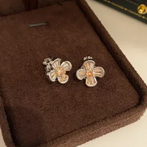 Detailopname van glinsterende perzik kristal bloem clip-oorringen in een fluwelen bruine doos.