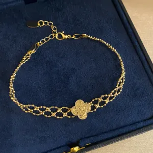 Close-up of the gold multi-strand clover bracelet showing its textured floral centerpiece.