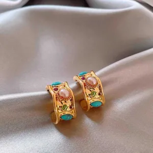 Close-up of vintage chunky gold hoop earrings featuring vibrant turquoise and pearl inlay.