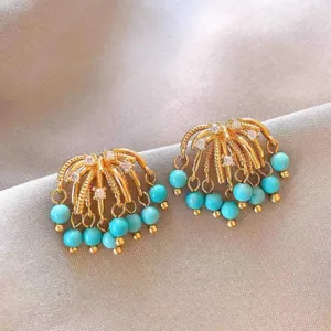 Vintage style turquoise bead tassel earrings detail close up, elegant gold metal jewelry design.