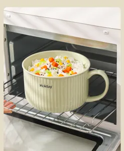 Vista dettagliata di una ciotola per noodle in ceramica verde chiaro con manico con cibo all'interno.