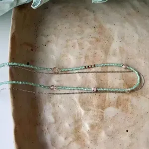 Détail en gros plan du collier superposé de perles vert menthe vintage aux chaînes.