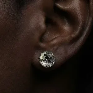 Close-up detail shot of sparkling faceted blue zircon stud earring worn on earlobe.