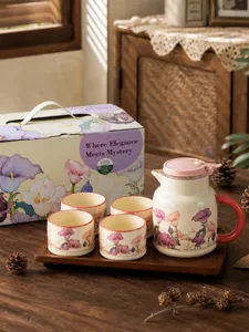 Vue détaillée d'un service à thé en céramique avec théière florale, tasses et plateau en bois.