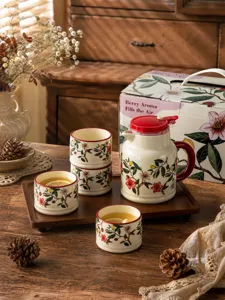 Detailed view of vintage ceramic tea set with floral print teapot, cups, and wooden tray.