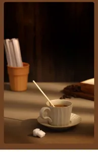 Close-up detail view of natural wooden coffee stirring stick in a cozy cafe scene setup.