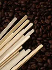 Wooden coffee stirrer detail shot, smooth bamboo texture on fresh roasted coffee beans background.