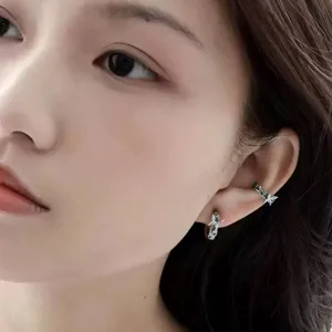 Close-up detail of silver ear cuff and stud worn on ear, fashionable metal jewelry design.