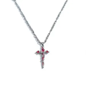 Collana con ciondolo croce pugnale gotico e cristalli rossi su catena metallica argentea.