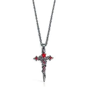 Dettaglio del ciondolo a croce gotica scura, con intagli di viti e un cuore in cristallo.