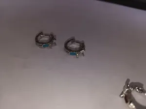 Close-up detail of mint green turquoise small hoop earrings with sparkling crystal bow design.
