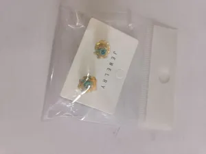 Gold-plated blue rose flower stud earrings with white display card and clear packaging.