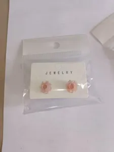 Detailed shot of sweet pink flower stud earrings with minimalist backing card and clear packaging.