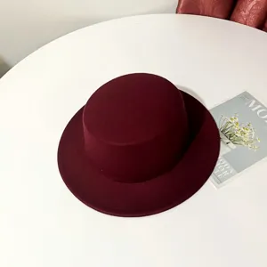 Detailed view of the dark red flat top wool felt hat, stylish British fedora cap accessory.