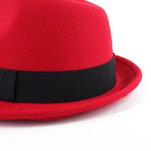Detalle de sombrero fedora de lana roja, sombrero estilo británico con cinta negra.
