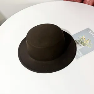 Close-up detail of the classic black woolen flat top hat showcasing the fine felt texture.