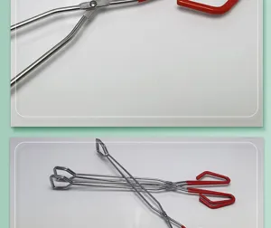 Detail view of stainless steel barbecue fire tongs with red handles for outdoor grilling.