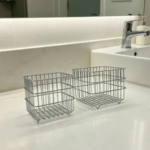 Detailed close-up view of modern metal wire storage baskets on clean marble countertop for home.