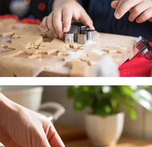 Detailed view of stainless steel cookie cutter in use, pressing festive shapes into dough.