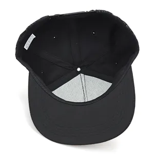 Interior detail view of black cotton snapback baseball cap showing lining and care label.