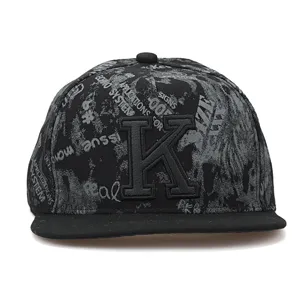 Detail view of black hip-hop cap with letter K and graffiti print, flat brim street fashion.