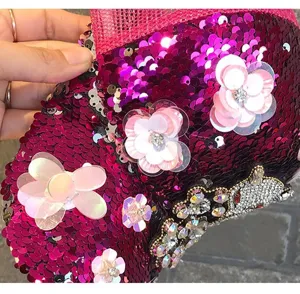 Close-up of hot pink sequin baseball cap detail with floral applique and rhinestone crown.