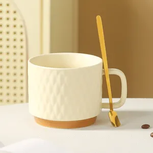 Close-up detail shot of elegant ceramic coffee cup with diamond pattern and golden spoon.