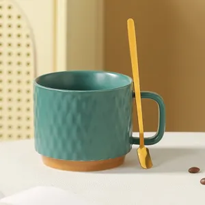 Detailed close-up of a ceramic coffee mug with unique hammer texture and a matching gold spoon.