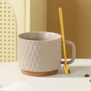 Ceramic coffee cup detail shot, embossed diamond pattern, brown bottom with gold spoon.