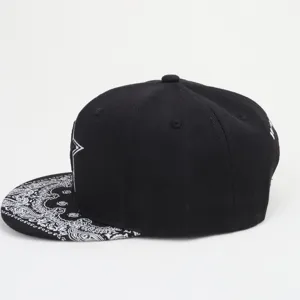 Casquette plate noire avec broderie d'étoile blanche et visière motif paisley chic.
