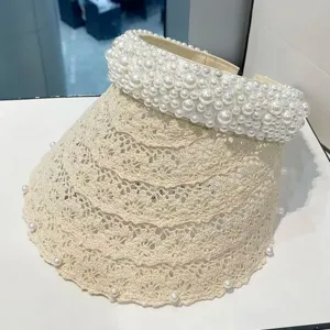 Vista detallada de un elegante sombrero de sol de encaje beige con hermosas perlas.