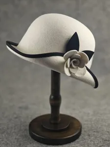 Detail view of elegant wool felt cloche hat with black trim and handmade camellia flower.