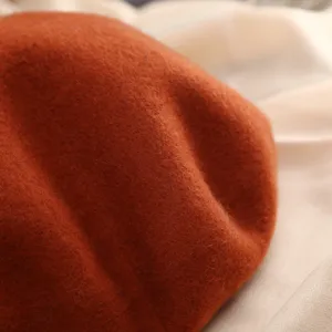 Gros plan d'un béret en laine orange douce montrant une texture feutrée et ton automnal.