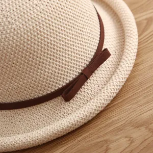 Primer plano detalle de sombrero de paja mujer primavera verano con lazo marrón en madera.