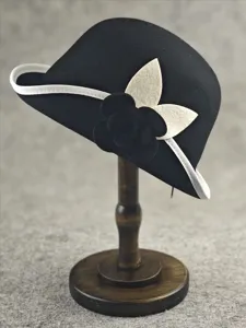 Detail view of black wool cloche hat with white trim and camellia flower, vintage Hepburn style.