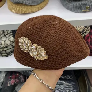 Détail de béret en résille marron avec broche cristal étincelante pour un style.