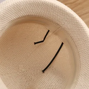 Primer plano de los detalles interiores del sombrero de paja beige con cinta elástica.